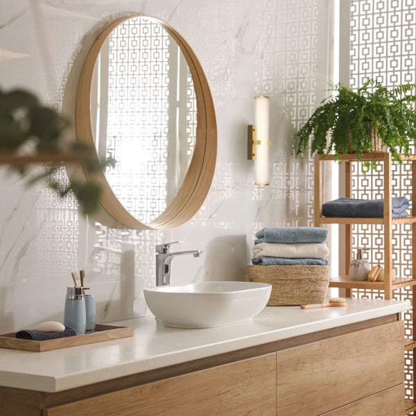 Badezimmer mit Waschtisch, rundem Spiegel, Handtüchern und Dekoration