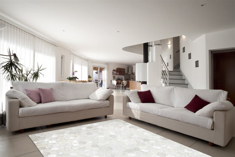 Geräumiges Wohnzimmer mit zwei Sofas und einem gemusterten Teppich in einem offenen, hell gestalteten Innenraum mit angrenzender Treppe.