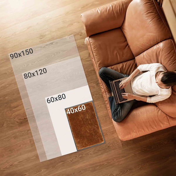 Darstellung verschiedener Teppichgrößen im Wohnzimmer neben einer Couch.