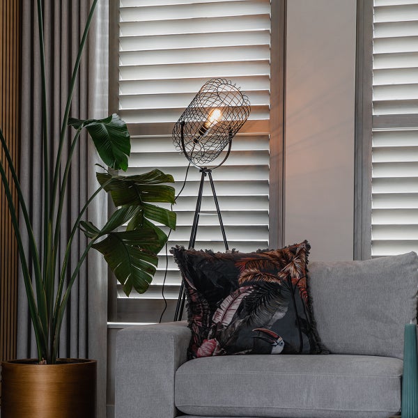 Dekoratives Wohnzimmer mit Stehlampe, Kissen und Zimmerpflanze