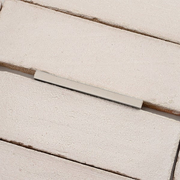Fliesenfuge mit einem metallischen Fliesenfugenprofil zwischen zwei Natursteinfliesen.