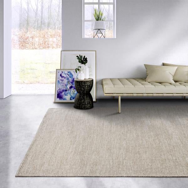 Szene mit Teppich, Sofa, Beistelltisch und Dekoration in einem hellen Raum.