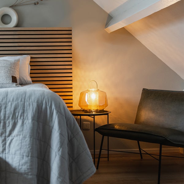 Schlafzimmer mit Bett, Beistelltisch und Tischleuchte