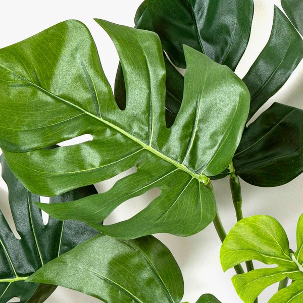 Nahaufnahme einer künstlichen Orchidee mit grünen Blütenknospen und einem Teil einer rosa-weißen Blüte.