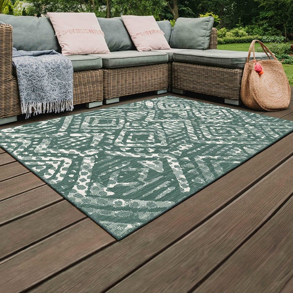 Rechteckiger Teppich mit geometrischem Rautenmuster und gepunkteten Details, eine Ecke umgeklappt.