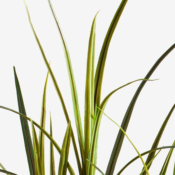 Nahaufnahme der langen, schmalen Blätter einer Kunstpflanze Gras in Grün und Braun.