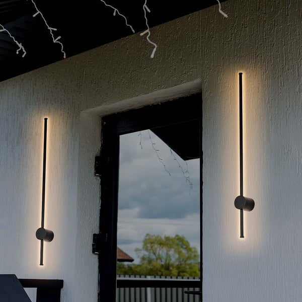 Zwei moderne Wandleuchten aus Metall für den Außenbereich neben einer Tür.