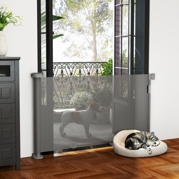 Innenaufnahme mit einem grauen, einziehbaren Haustiergitter vor einer Balkontür, einem Hund und einer Katze