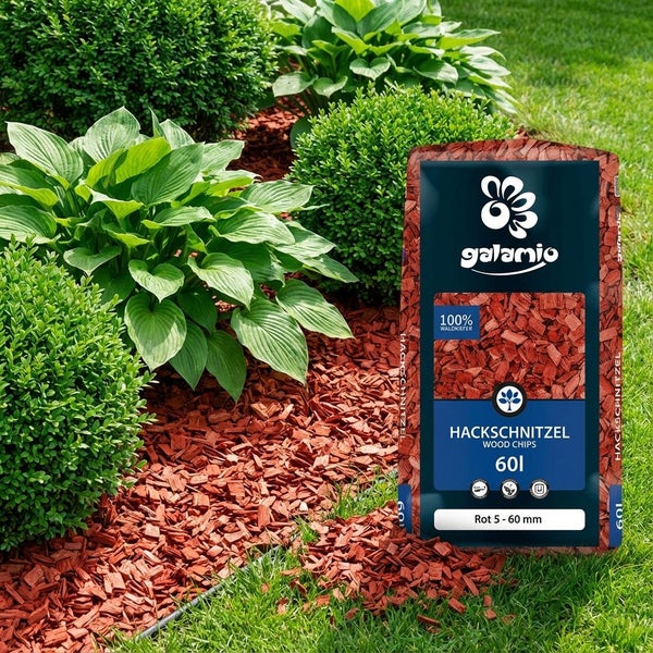 Eine Packung Galamio Rindenmulch Holzhackschnitzel mit 60 Litern Inhalt vor einem Gartenbeet mit Sträuchern und Rindenmulch.