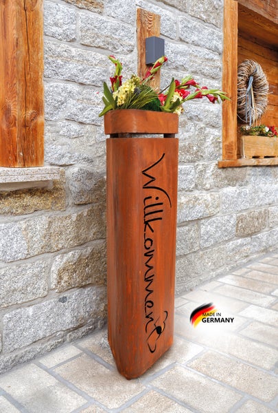 Pflanzsäule aus Edelrost mit Schriftzug Willkommen vor einer Natursteinmauer stehend inklusive Made in Germany Siegel