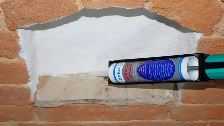 Kartuschenpresse beim Auftragen von beko Silikon Dichtstoff in einer Mauerwerksfuge.