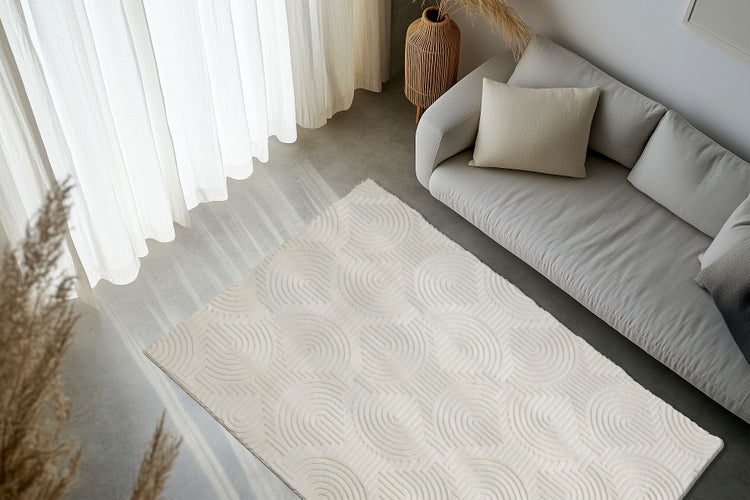 Wohnzimmer mit modernem Teppich mit geometrischem Bogenmuster vor einem Sofa auf einem Betonboden.
