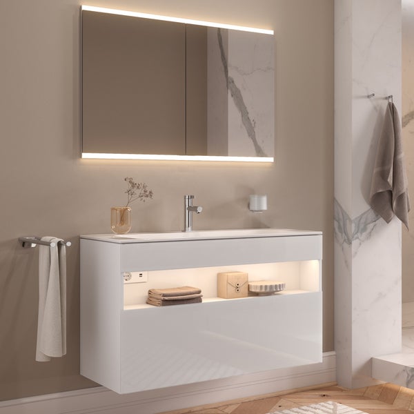 Modernes Badezimmer mit weißem Waschtischunterschrank, beleuchtetem Spiegelschrank, Armatur und Handtuchhalter in einem minimalistischen Design.