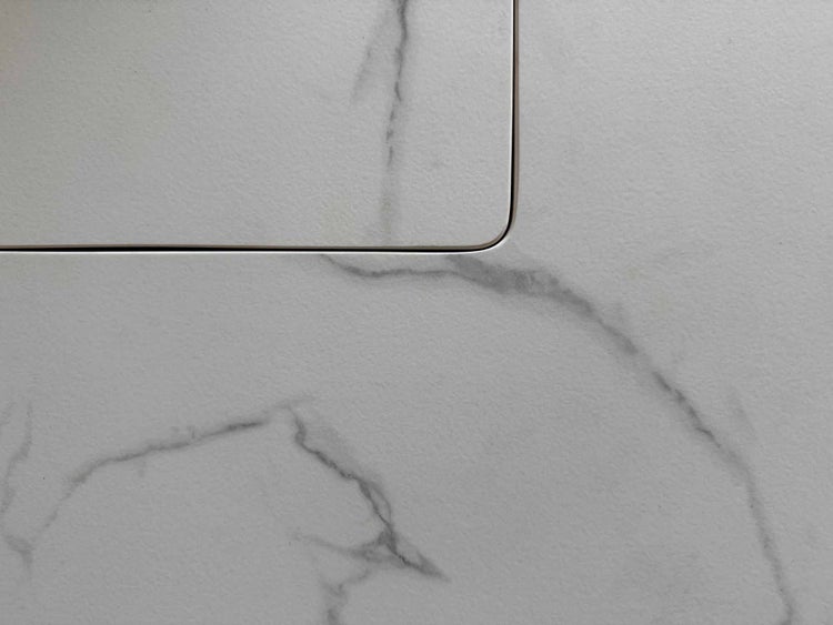 Nahaufnahme einer Oberfläche in Marmor-Optik mit einer bündig eingelassenen Abdeckung.