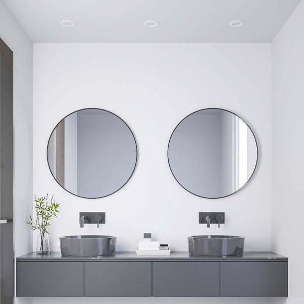Modernes Badezimmer mit Doppelwaschtisch, zwei runden Spiegeln, grauen Aufsatzwaschbecken und schwarzen Wandarmaturen auf einem grauen Unterschrank.