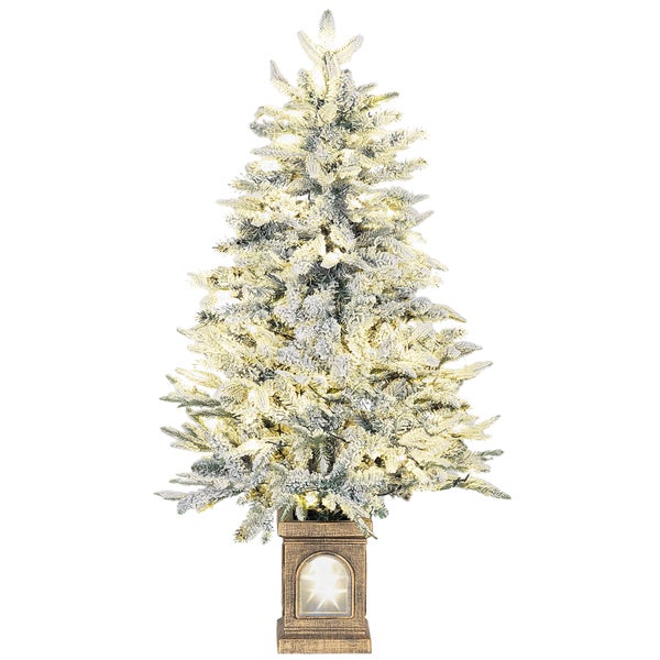 Verschneiter künstlicher Weihnachtsbaum mit warmweißer Beleuchtung und einem beleuchteten dekorativen Sockel.
