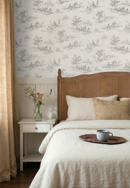 Vliestapete mit Toile-de-Jouy-Muster in einem hellen Schlafzimmer mit Holzbett, weißem Nachttisch und klassischem Design.