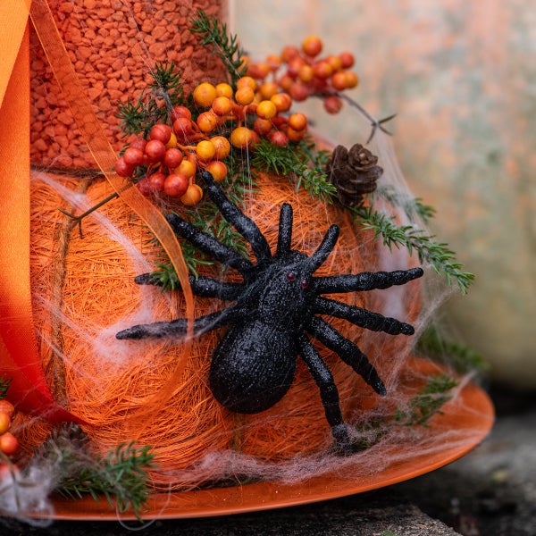 Halloween Dekoration mit Spinne und Beeren auf einem orangefarbenen Kürbis