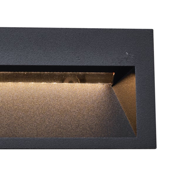 Detailansicht einer schwarzen LED-Außenwandleuchte mit strukturierter Oberfläche und warmem Lichtauslass.