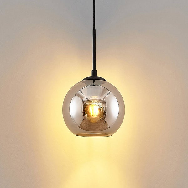 Moderne Pendelleuchte mit kugelförmigem Schirm aus Rauchglas und schwarzer Aufhängung, warm strahlendes Licht.