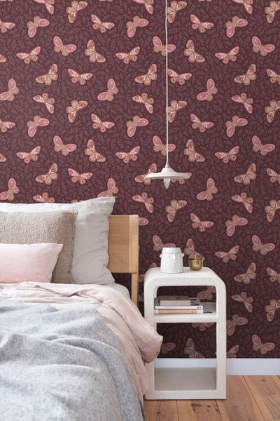 Schlafzimmer mit Bett und Nachttisch vor Tapete mit Schmetterlingsmuster