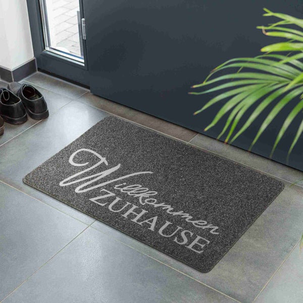 Fußmatte mit der Aufschrift Willkommen Zuhause vor einer Haustür