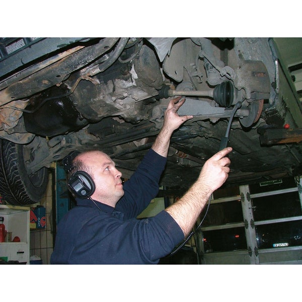 Ein Mechaniker unter einem Auto, der ein elektronisches Stethoskop benutzt, um Geräusche zu diagnostizieren.