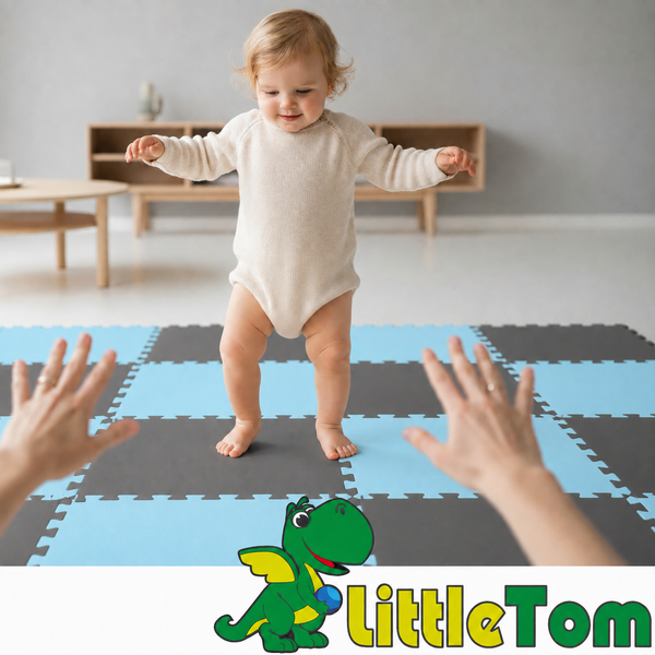 Ein Kleinkind steht auf einer Puzzlematte aus Schaumstoff in einem hellen Raum, während zwei Hände zum Auffangen bereit sind. LittleTom Logo.