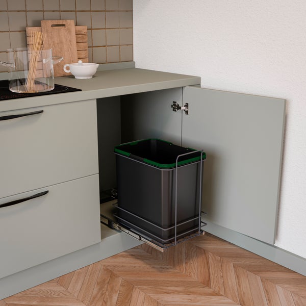 Einbau-Abfalleimer in einem Küchenunterschrank mit Auszugsystem auf Metallschienen. Ein grauer Abfallbehälter mit grünem Rand.