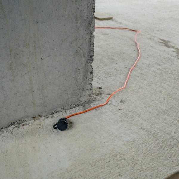 Oranges Verlängerungskabel mit Stecker auf Betonboden