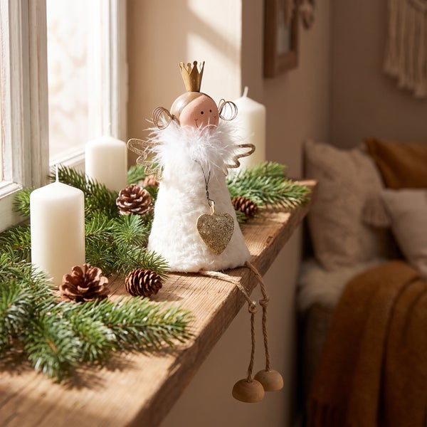 Weihnachtsdekoration Engel mit Krone Herz und Pelzoptik auf einem Fensterbrett mit Tannengrün und Kerzen