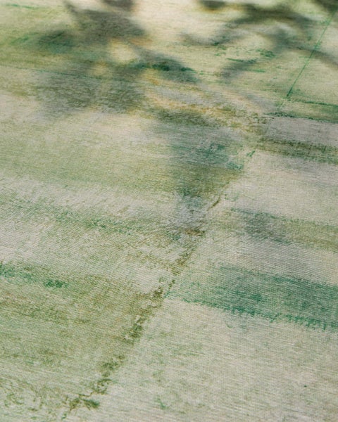 Teppich mit abstraktem Muster in Grün und Beige, strukturierte Oberfläche in Nahaufnahme.