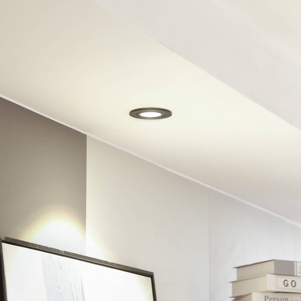 Ein runder LED Einbaustrahler ist bündig in eine Decke eingelassen und beleuchtet hell einen modern gestalteten Innenraum.