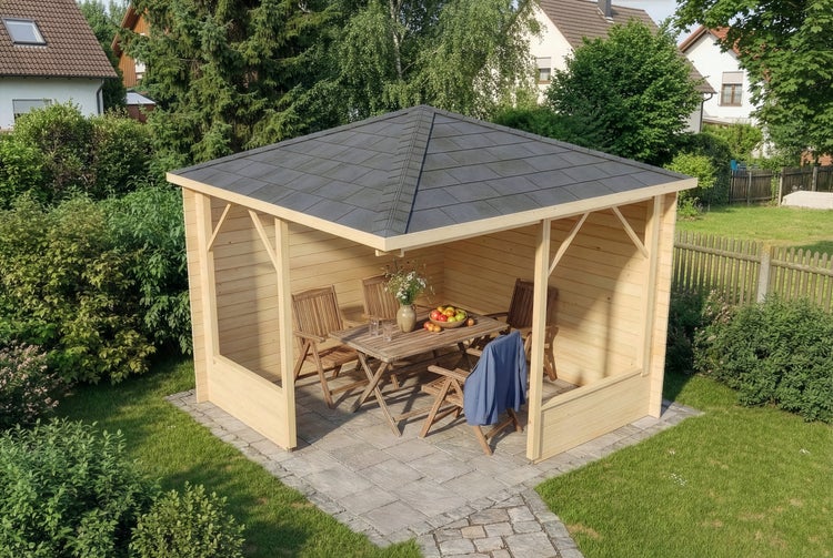 Offener Gartenpavillon aus hellem Holz mit grauem Schindeldach, Holztisch und Stühlen auf einer gepflasterten Terrasse im Garten.