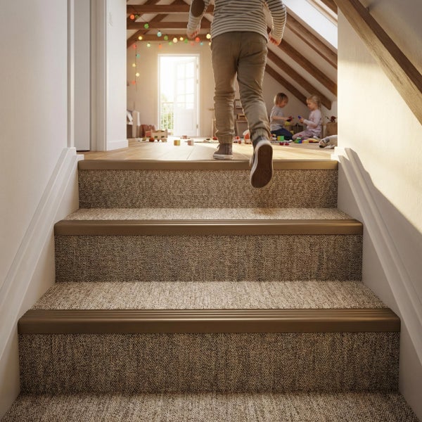 Treppenstufen mit textilen Stufenmatten und Kantenprofilen in einem hellen Dachgeschoss, in dem Kinder auf dem Holzboden spielen.