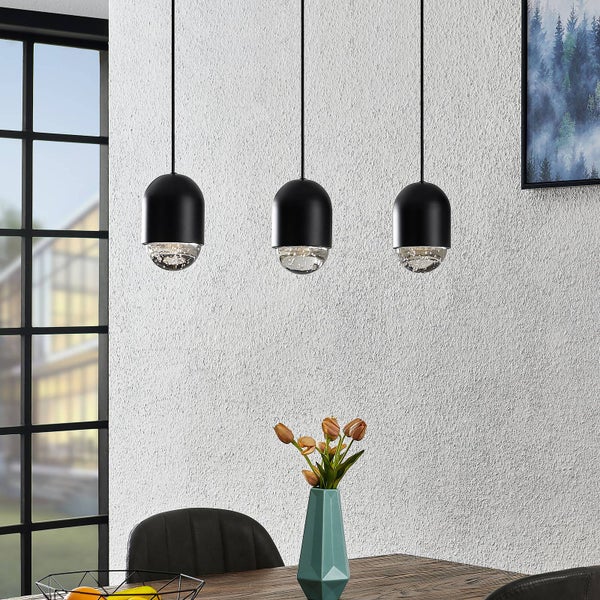 Esstisch mit drei schwarzen Pendelleuchten und einer Vase mit Blumen