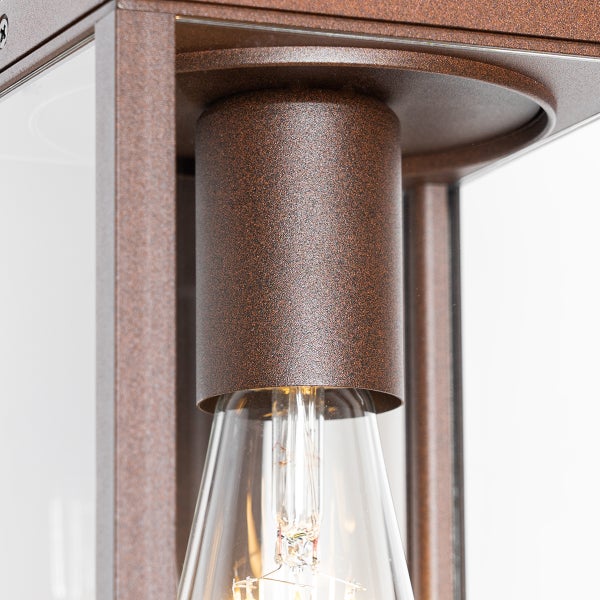 Detailansicht einer Außenwandleuchte mit Metallgehäuse in Rostoptik, Glasscheiben und einem sichtbaren LED-Leuchtmittel.