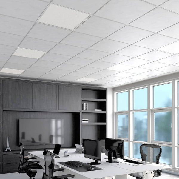 Moderner, heller Büroraum mit weißer Rasterdecke und integrierten quadratischen LED-Panels. Schreibtische mit Monitoren und ergonomische Stühle.