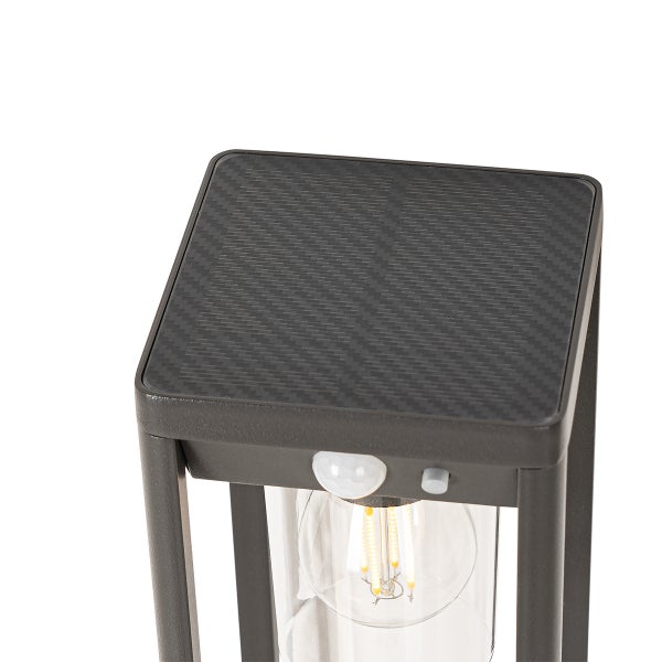 Detailansicht einer Solarleuchte mit Solarpanel auf der Oberseite, Bewegungssensor und LED-Filament-Leuchtmittel.