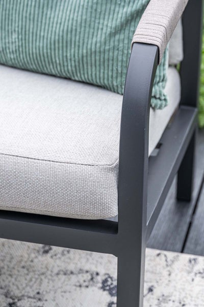 Detailansicht eines Gartenstuhls mit gepolsterter Sitzfläche und einer mit Seil umwickelten Armlehne auf einem Metallgestell.