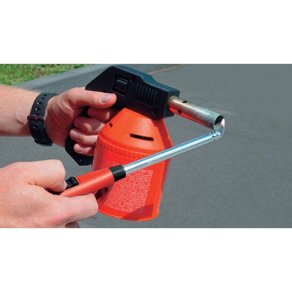 Person entzündet eine Lötlampe mit einem Stabfeuerzeug im Außenbereich.