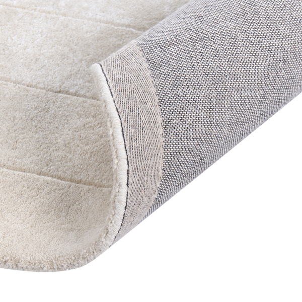 Heller Wohnzimmerteppich mit geometrischem Linienmuster auf einem Holzboden neben einem geschwungenen Bouclé-Sofa in einem hellen, modernen Raum.