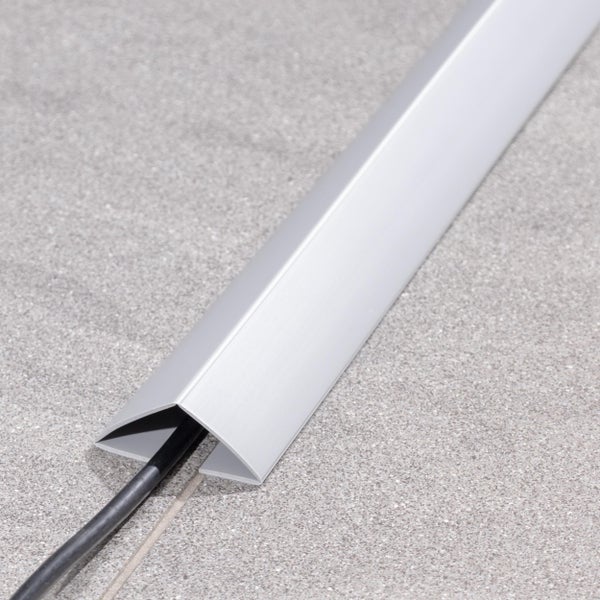 Aluminium Kabelkanal als Bodenprofil mit eingezogenem schwarzen Kabel auf einem Fliesenboden