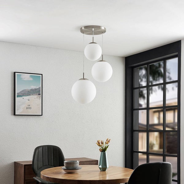 Moderne Pendelleuchte mit drei Lampenschirmen in Kugelform über einem Esstisch.