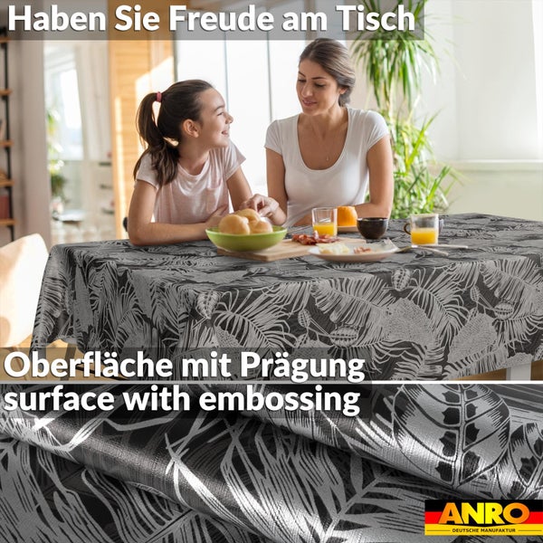 Frau und Kind an einem Tisch mit einer schwarz-silbernen Tischdecke mit Palmenblattmuster. Geprägte Oberfläche. ANRO Logo.
