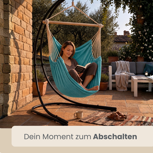 Frau liest in einem Hängesessel mit schwarzem Metallgestell auf einer Terrasse