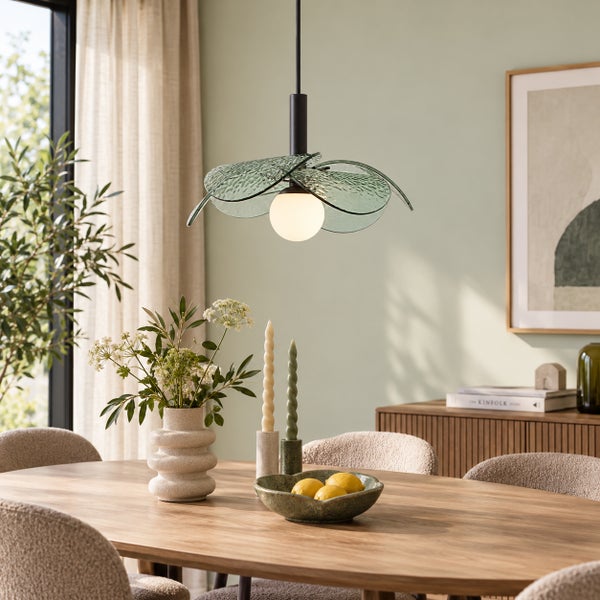 Moderne Pendelleuchte mit blütenförmigem Glasschirm über einem Esstisch in einem hellen, natürlich gestalteten Esszimmer.