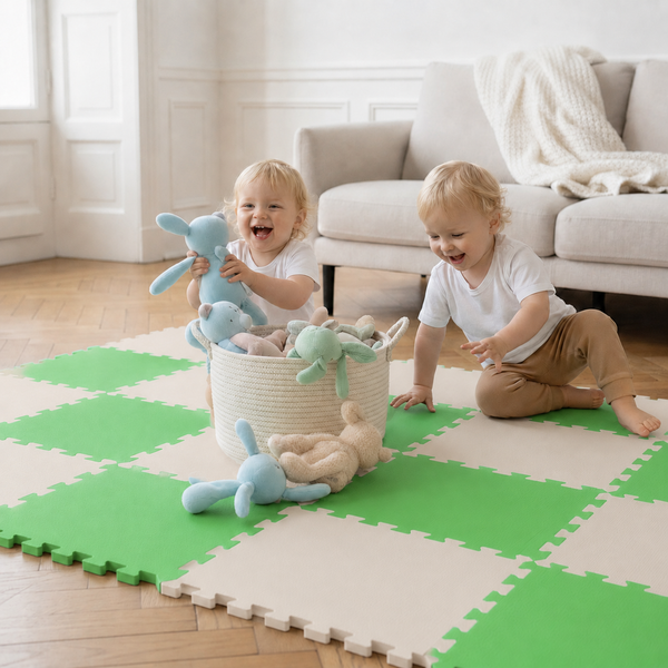 Zwei Kleinkinder spielen auf einer zusammensteckbaren Puzzlematte mit Stofftieren in einem hellen Wohnzimmer mit Sofa.