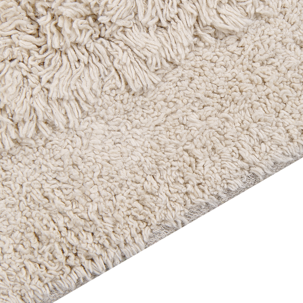 Detailansicht einer beige strukturierten Badematte mit Hochflor und Fransen.