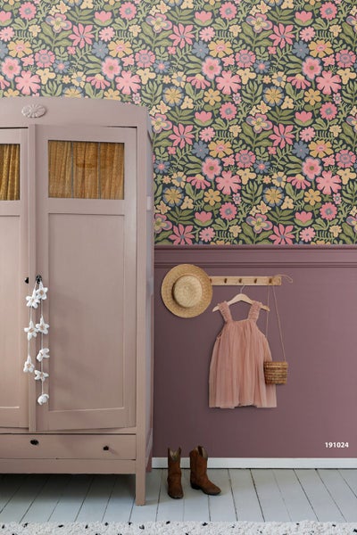 Vliestapete mit bunten Blumenmustern über einer lila Wandpaneele mit einem Kleiderschrank und Kinderkleidung.